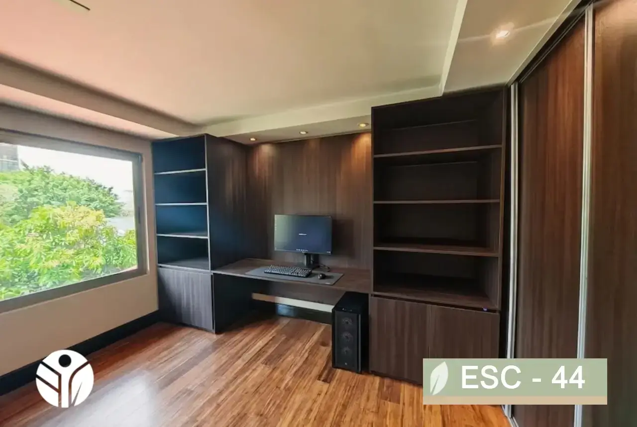 Escritorio de madera oscura con libreros laterales e iluminación LED integrado en oficina de Costa Rica.
